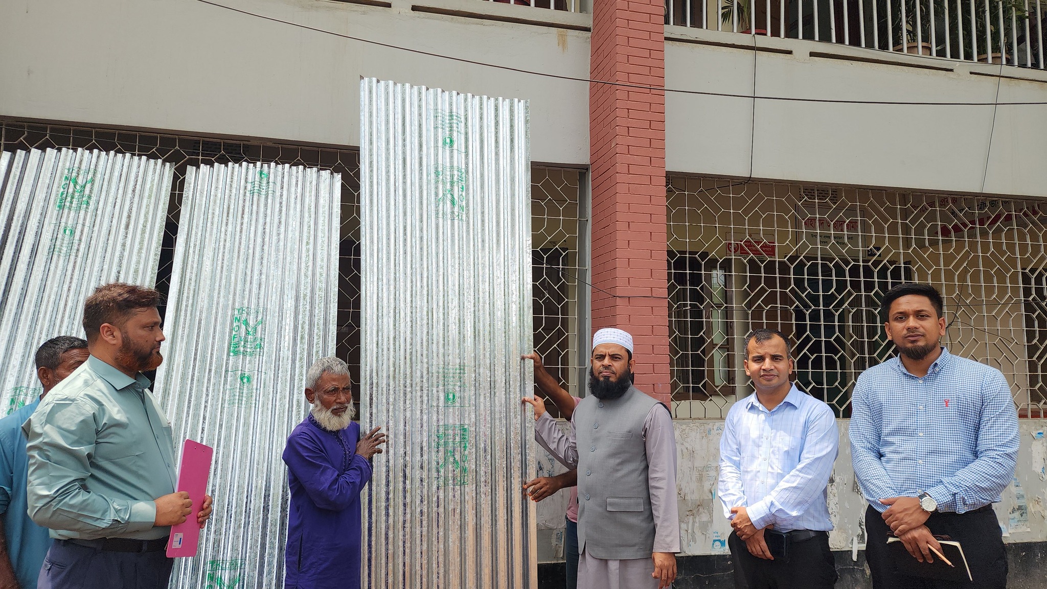 Distribution of corrugated tin and cash among 10 helpless families in Srimangal